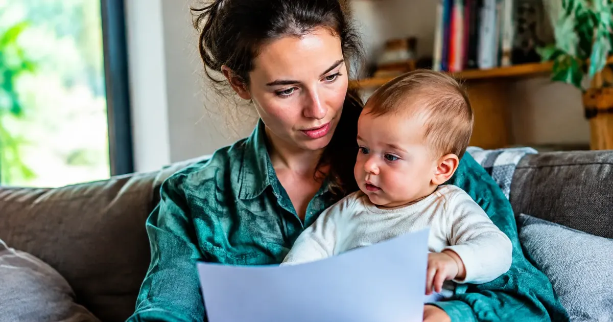 Donna seduta con bambino piccolo in braccio consulta documento
