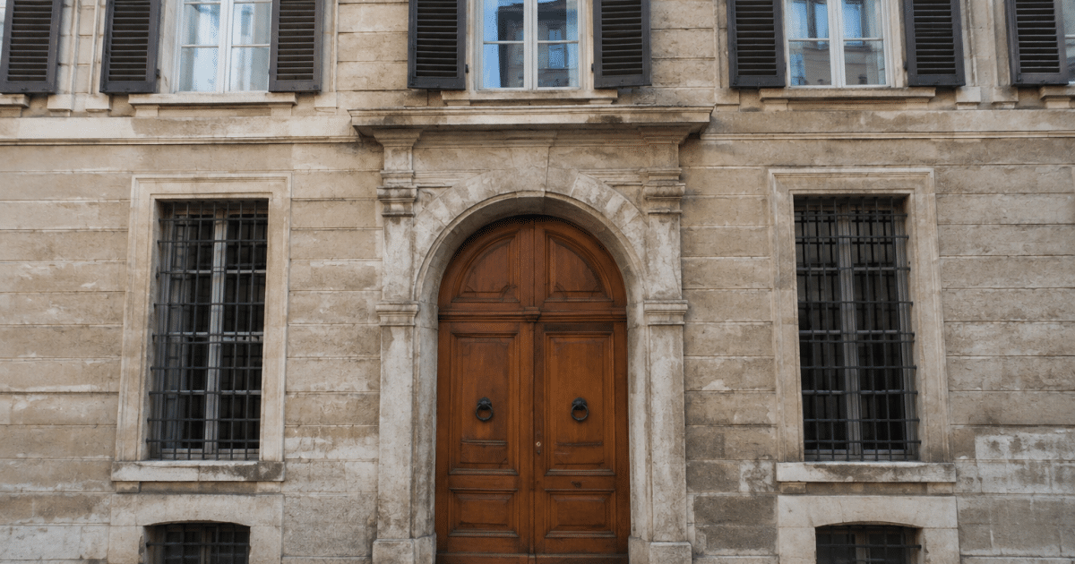 Facciata storica di palazzo con finestre alte e portone d'ingresso in legno