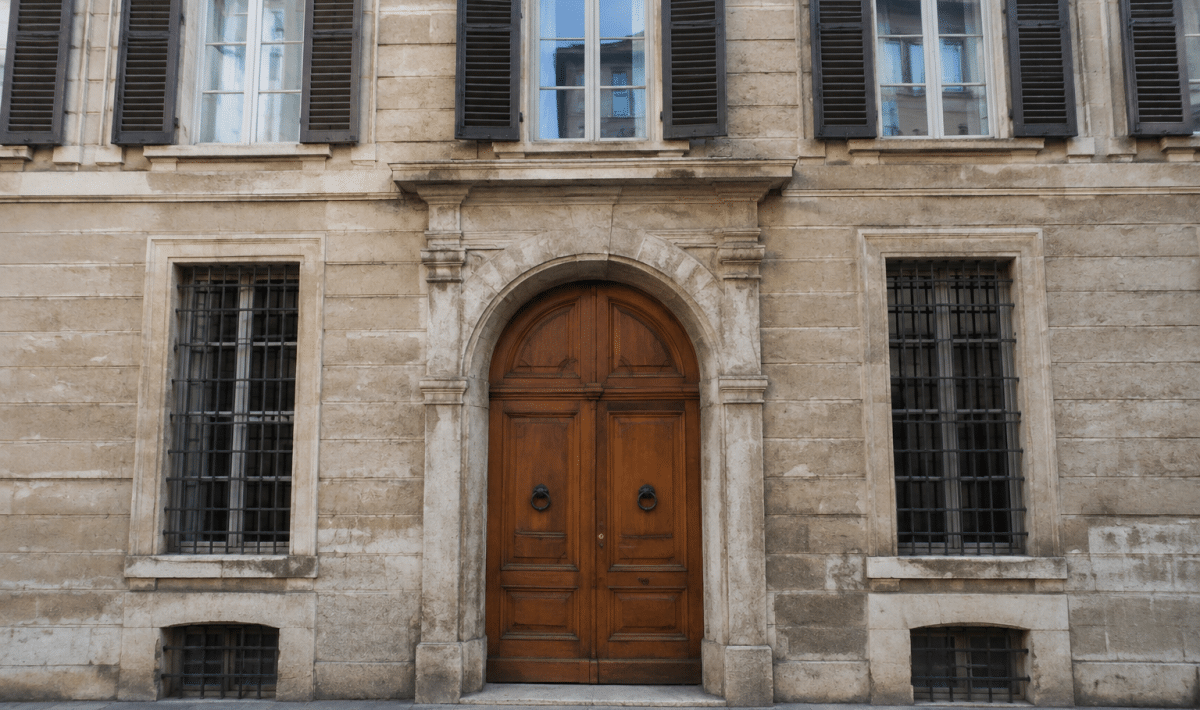 Facciata storica di palazzo con finestre alte e portone d'ingresso in legno