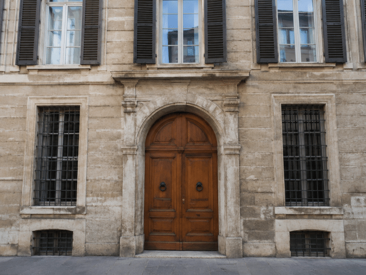 Facciata storica di palazzo con finestre alte e portone d'ingresso in legno