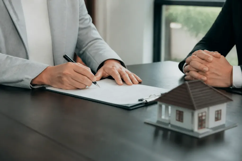 Documento firmato con penna su scrivania immobiliare.
