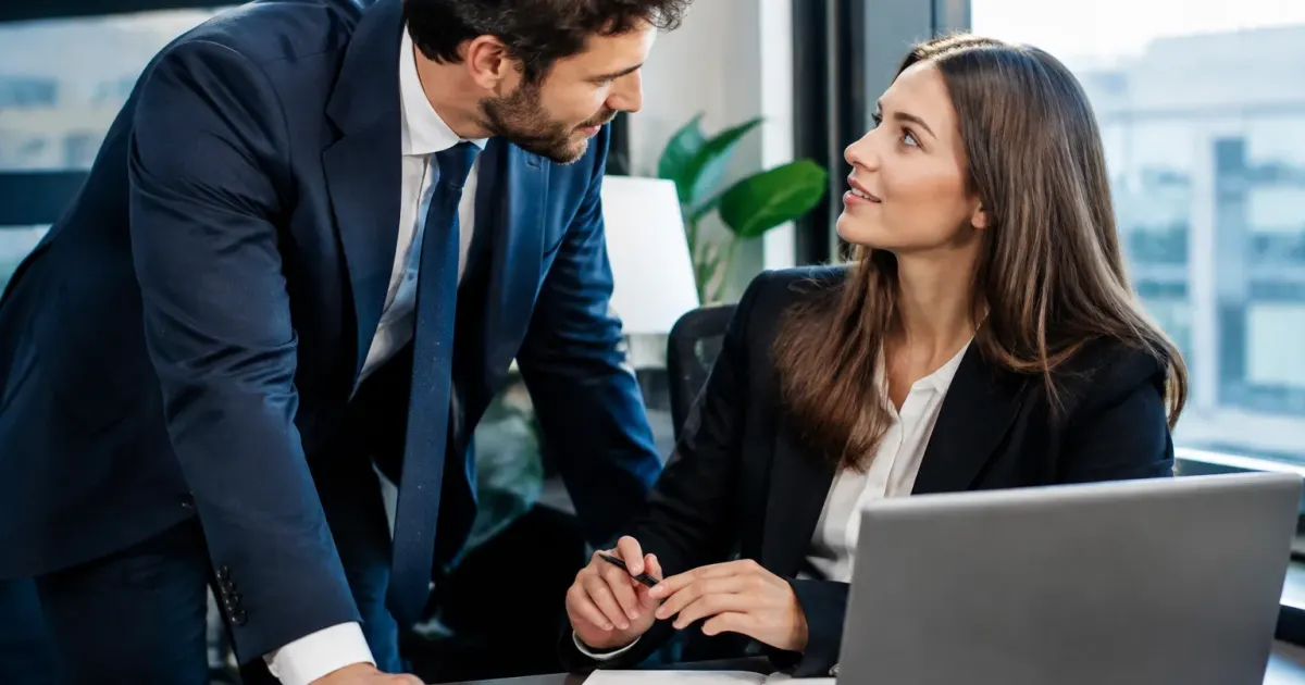 Uomo in completo inclinato rivolto collega seduta tavolo